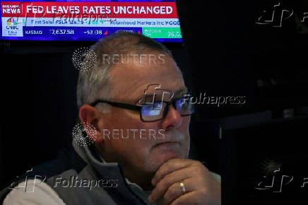 A screen displays the Fed rate announcement as traders work on the floor of the NYSE in New York