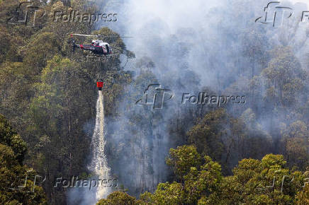 Helicóptero da Polícia Militar joga água em área de queimadas em Perus, em São Paulo