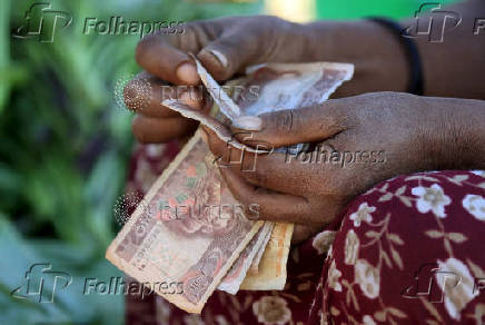 FILE PHOTO: A woman counts Ethiopian birr notes, after selling a cabbage at the Mercato market in Addis Ababa