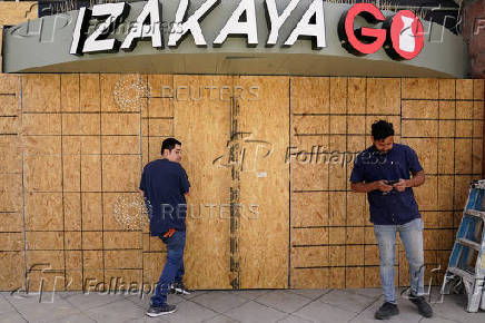 Workers board up a restaurant after days of protests against federal immigration sweeps in Los Angeles