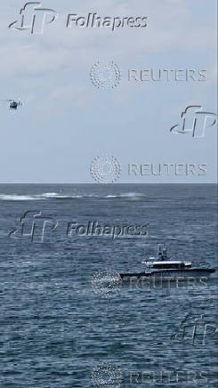 Emergency services vessels and a helicopter are deployed, following an incident at Long Reef Beach where a surfer died after being attacked by a large shark