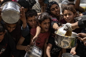 Displaced Palestinians collect donated food in Jabalia, northern Gaza