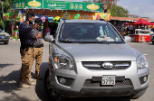 Members of Syrian Tourism Police speak with people in a car in Latakia
