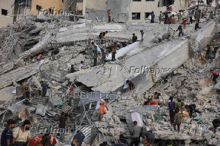 Palestinians inspect the site of an Israeli air strike that destroyed a residential building, in Gaza City