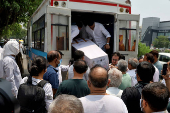 People unload a coffin containing the remains of Megha Mehta for her cremation in Ahmedabad