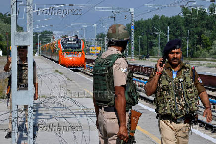 Security force personnel stand guard as India's high-speed train