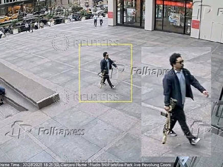 A man holding a rifle walks into an office building shortly before a shooting that killed several people in Manhattan