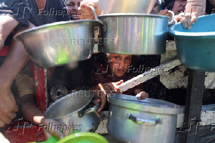 Palestinians wait to receive food from a charity kitchen, in Gaza City