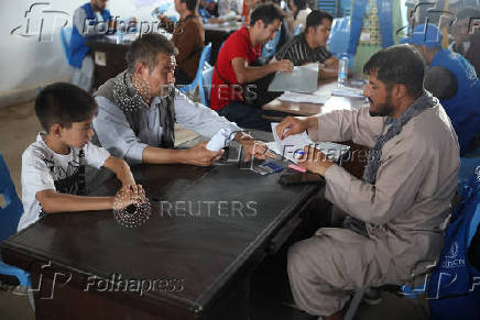 Afghan nationals, who were deported from Iran, register themselves in a UNHCR tent at a camp for returning migrants near the Islam Qala border crossing
