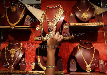 FILE PHOTO: A saleswoman keeps a gold necklace in a shelve at a showroom in Mumbai