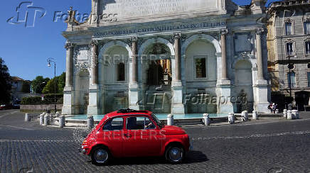 FILE PHOTO: A man drives an old Fiat 500 past the monumental fountain Dell'Acqua Paola known as 