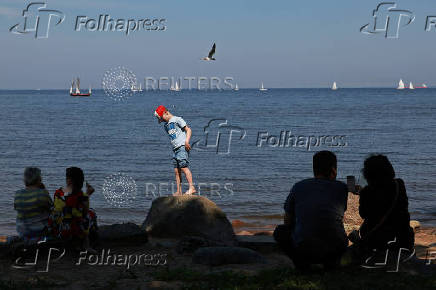 People watch yachts sailing through the Gulf of Finland in Saint Petersburg