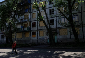 A resident walks at a street near buildings damaged by Russian military strikes in the frontline town of Kostyantynivka