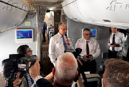 Newly elected German Chancellor Friedrich Merz talks to journalists on a plane en route to France