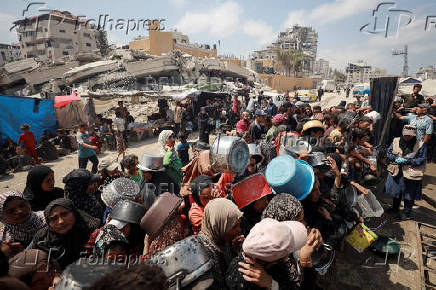 Palestinians wait to receive food from a charity kitchen, in Gaza City