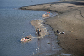 FILE PHOTO: Fishermen clear a fishing net in the water on the partially dried up of the Indus River in Hyderabad
