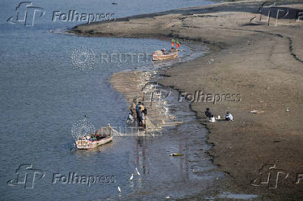 FILE PHOTO: Fishermen clear a fishing net in the water on the partially dried up of the Indus River in Hyderabad