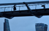 FILE PHOTO: City workers cross the Millennium footbridge in the financial district of London