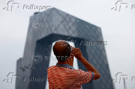 A person takes pictures on a terrace of a shopping mall overlooking the central business district (CBD), in Beijing