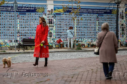 People walk near the Memory Wall of Fallen Defenders of Ukraine outside Saint Michael's Cathedral in Kyiv