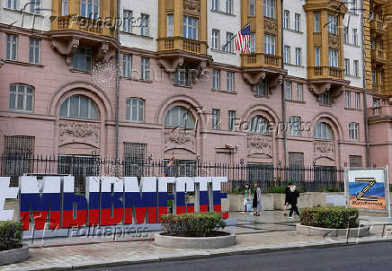 People walk past a banner depicting the symbol 