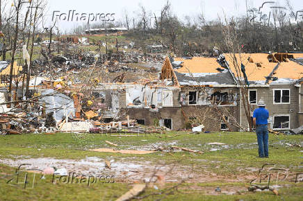 A man looks at debris on the ground after apartments were struck by a tornado in Selmer