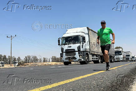 A man jogs on a road as trucks carrying aid arrive at the Kerem Shalom crossing between Israel and Gaza, on its Israeli side