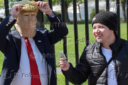A tourist pays a tip to Donald Trump impersonator Ed Weiskopf after posing for a photo in front of the White House in Washington