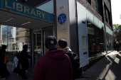 People walks past the John Harvard blue plaque outside the John Harvard Library on Borough High Street, London