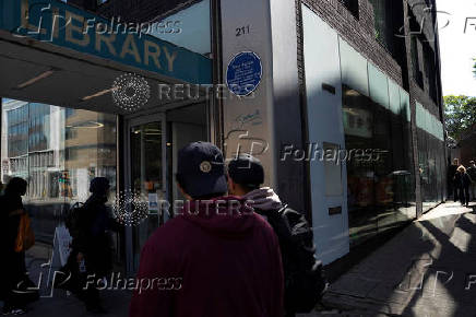People walks past the John Harvard blue plaque outside the John Harvard Library on Borough High Street, London