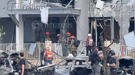 Emergency services officials inspect damage to buildings hit following a missile strike from Iran, in Be'er Sheva