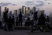 FILE PHOTO: People look towards Canary Wharf from Greenwich Park in London