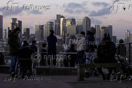 FILE PHOTO: People look towards Canary Wharf from Greenwich Park in London