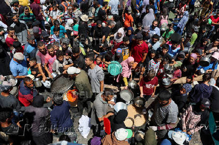 Palestinians gather to receive food from a charity kitchen, amid a hunger crisis, in Nuseirat
