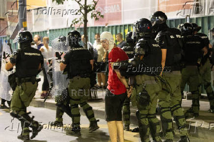 Serbian police detain a demonstrator during standoff between ruling party supporters and anti-government protesters in Belgrade