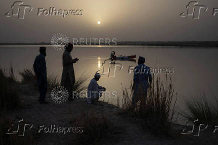 Fishermen set nets as men prepare to camp along bank of Chenab River in Multan, Pakistan