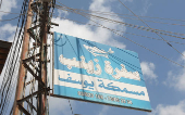 A roadsign hangs on an electricity pole reading  'Zainab's table', in the town of Sarafand