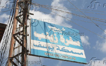 A roadsign hangs on an electricity pole reading  'Zainab's table', in the town of Sarafand