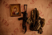 A machine gun and a flak jacket of a Ukranian serviceman are seen on a wall next to an icon near the frontline town of Chasiv Yar