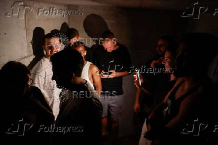 People take cover in a bomb shelter as a siren is heard, in Ashkelon
