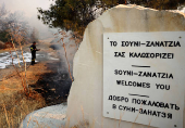 A firefighter uses a hose to cool a burnt area during a wildfire at the area of Souni, near Limassol