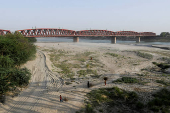 People walk on the dry riverbed of the Indus River in Hyderabad, Pakistan