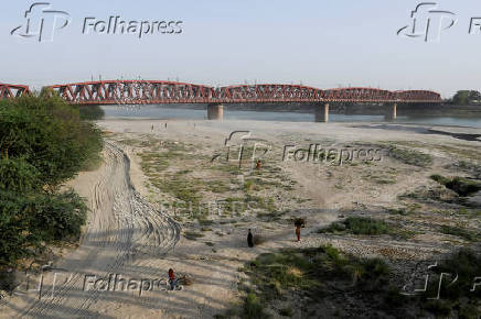 People walk on the dry riverbed of the Indus River in Hyderabad, Pakistan