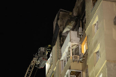 A firefighter inspects the damage at an apartment building, that was set partially ablaze by falling debris, following a Russian drone attack in Kyiv