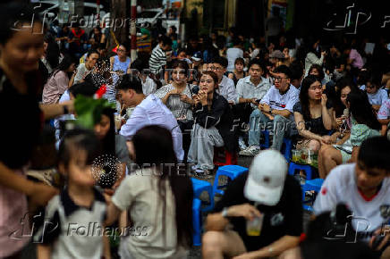 People sit near St. Joseph's Cathedral, in Hanoi