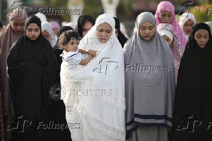 An Indonesian Muslim woman carries her daughter as she offers Eid al-Adha prayers at Baiturrahman mosque in Banda Aceh
