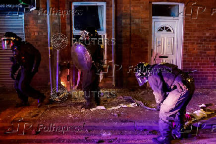 Armed police in riot gear stand guard during a second night of riots, in Ballymena
