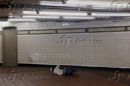 A person sleeps on the floor of a public subway station in Manhattan, New York City