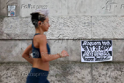 FILE PHOTO: A woman runs past a poster stuck on a wall which reads 