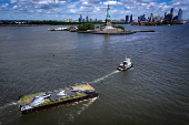 Drone view shows a grass covered barge with painting by Franco-Swiss artist Saype entitled ?Address Hate? towed past the Statue of Liberty in New York Harbor